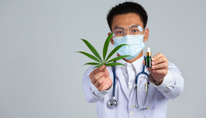 medico segurando a folha de cannabis e uma garrafa de oleo de cannabis na parede branca1 Maconha e Depressão: Explorando a Relação Entre o Uso de Cannabis e os Transtornos Depressivos